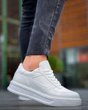 White sneakers worn with dark jeans on a blurred background