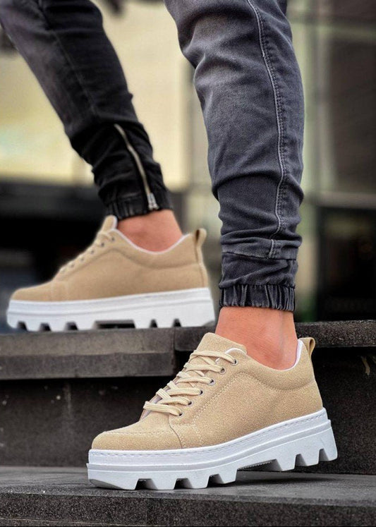 Beige sneakers with white soles worn by a person on steps.