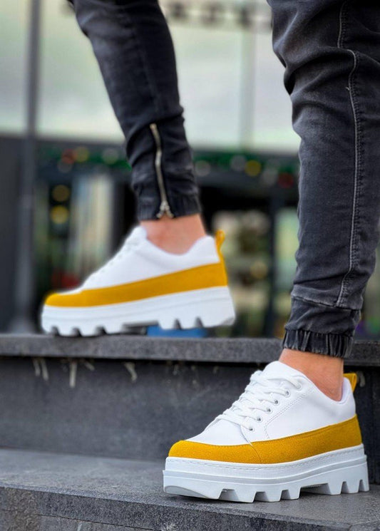 White sneakers with yellow accents worn by a person on steps.