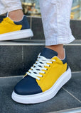 Yellow and navy sneakers with white soles worn on a step.