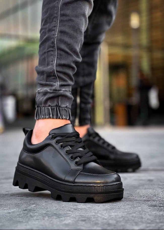 Black leather shoes worn with gray pants on a blurred street background