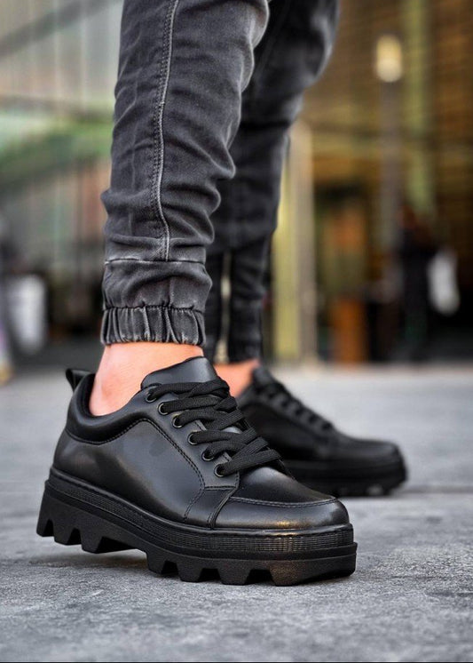 Black leather shoes worn with gray pants on a blurred street background