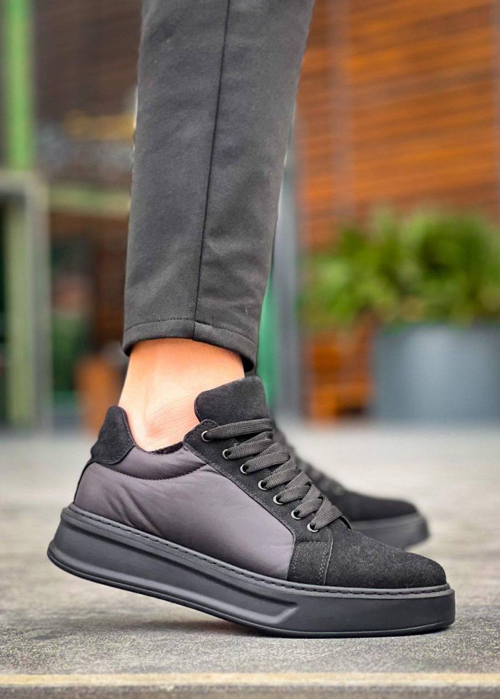 Gray sneakers worn with gray pants on a blurred outdoor background