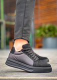Gray sneakers worn with gray pants on a blurred outdoor background
