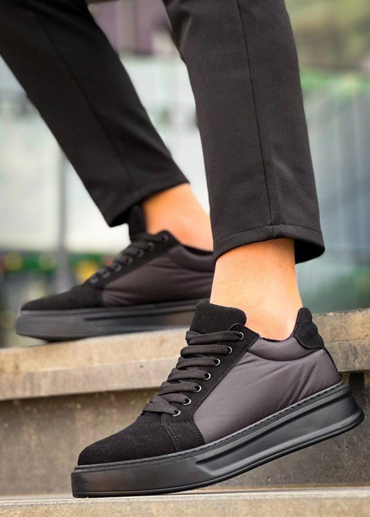 Black sneakers worn on a blurred outdoor background