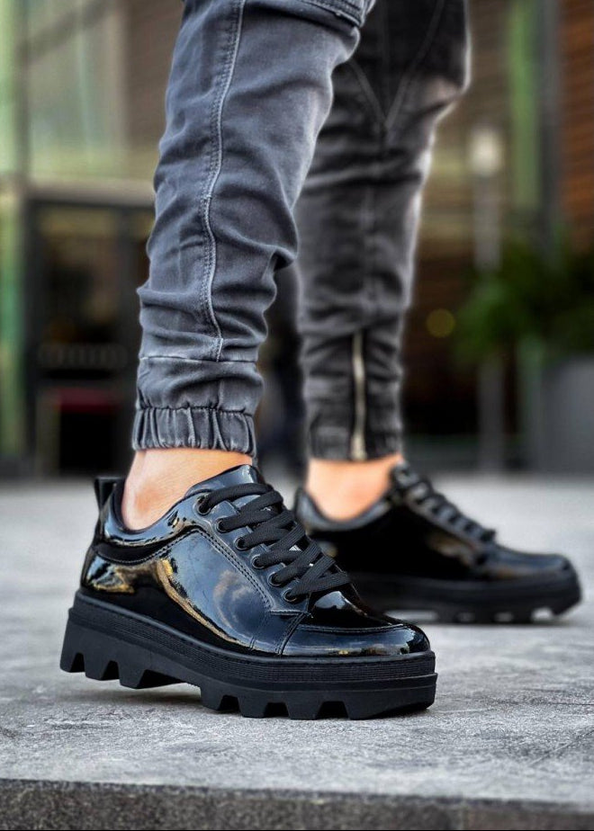 Black glossy sneakers worn with gray pants on a blurred background