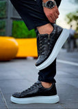 Black crocodile-patterned sneakers with white soles worn on a blurred street background