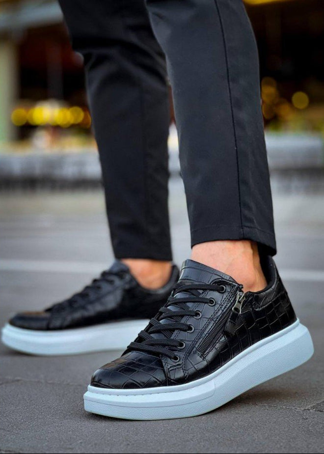 Black high-top sneakers with white soles worn by a person on a blurred background