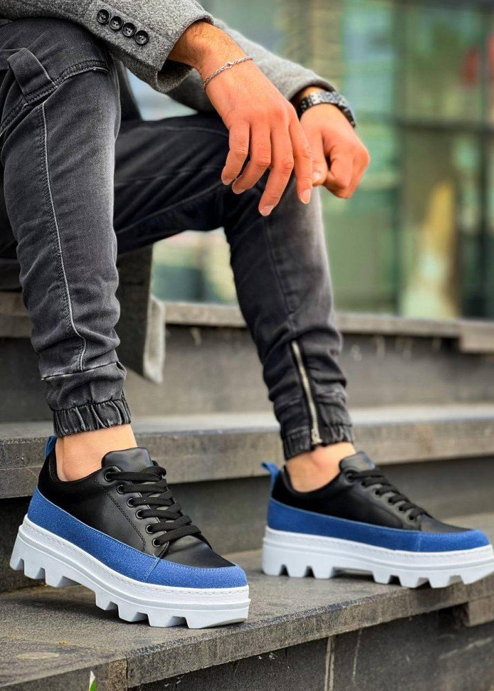 Black and blue sneakers with white soles worn by a person on steps.