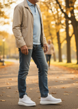Person walking in a park with autumn foliage in a pair of white knit Torino sneakers with a thick sole and laces, designed by Apollo Moda.