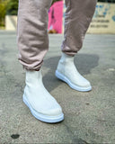 White Apollo Moda Torino X boots worn with light pink pants on a concrete surface.